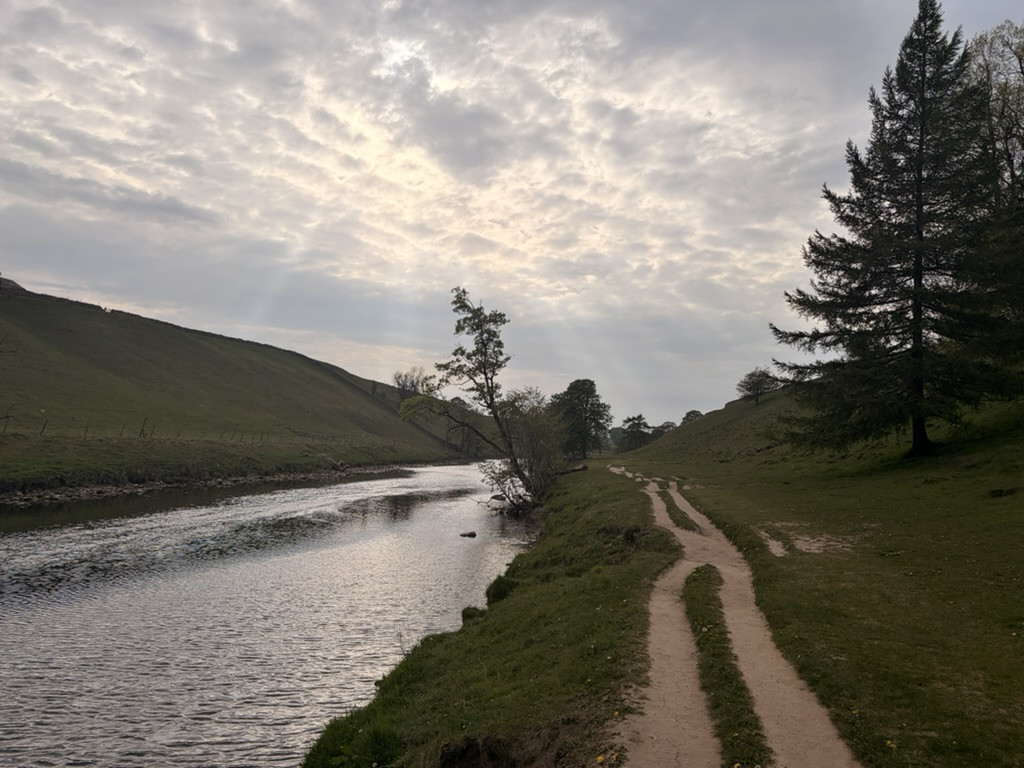 Peaceful riverside track winding beside the River Wharfe near the end of the Malham to Grassington walk