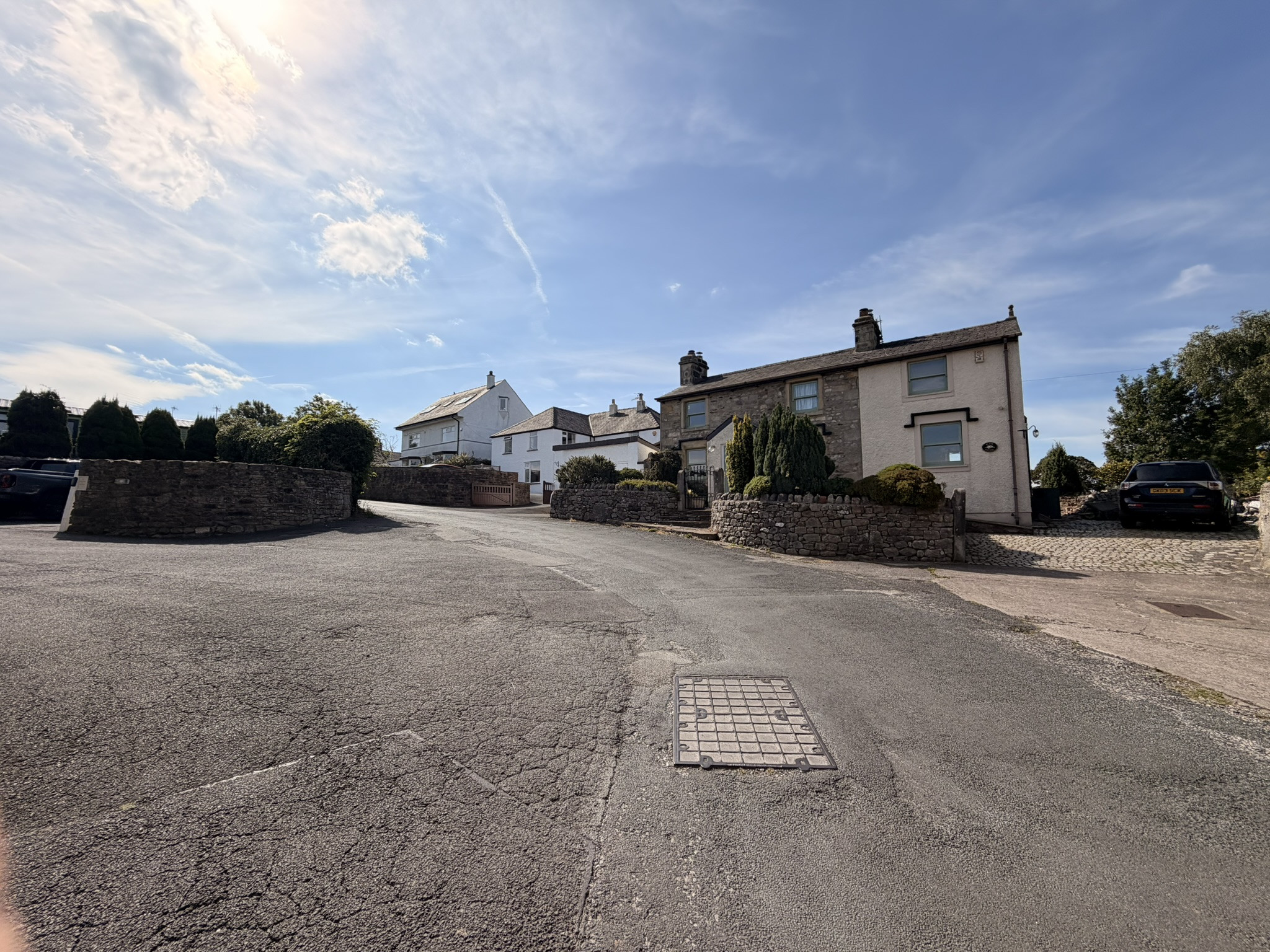 Quiet country-lane junction lined with stone walls and cottages on the route inland from Morecambe Bay