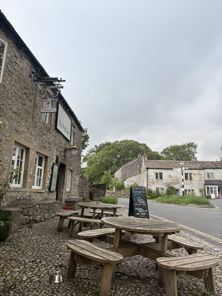 The stone-built Buck Inn in Malham with wooden picnic tables outside at the end of the walk