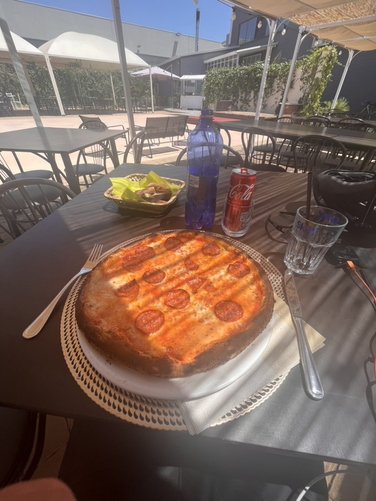 A freshly baked pizza served on a shaded restaurant terrace in San Vito dei Normanni.